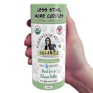 A hand holding a no rinse dog shampoo by Momma Knows Best unscented