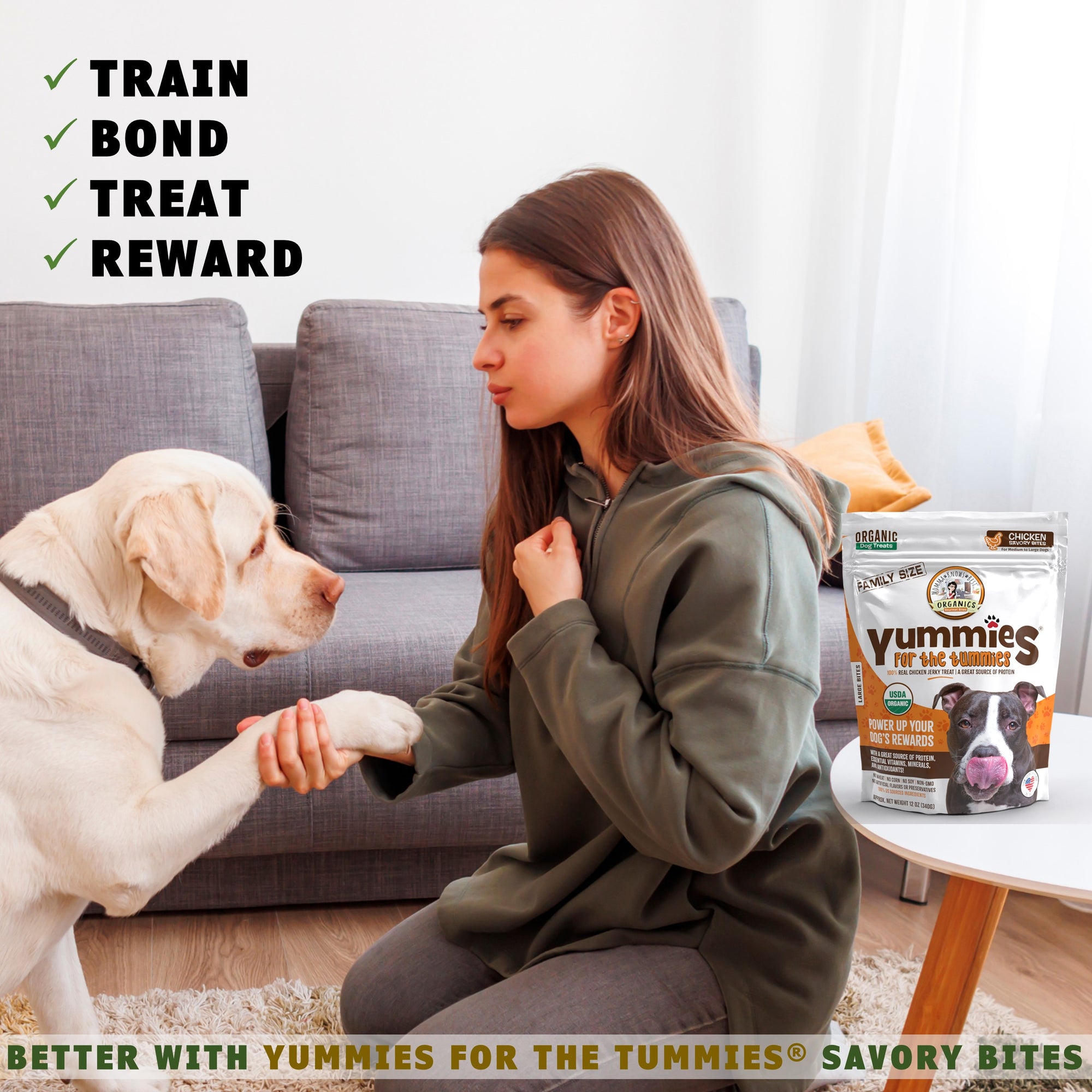 A person sitting on the floor with a dog next to a bag of organic dog chicken treats Yummies for the Tummies by Momma Knows Best organics 